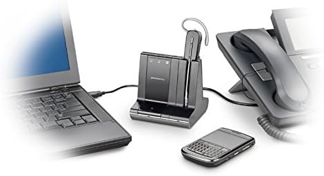 A laptop, a desk phone, a Poly Plantronics Savi W740 Wireless Headset System with its charging base, and a smartphone with a physical keyboard are placed on a desk. The devices are connected by various cables, showcasing a typical office setup that supports seamless 3-way connectivity.